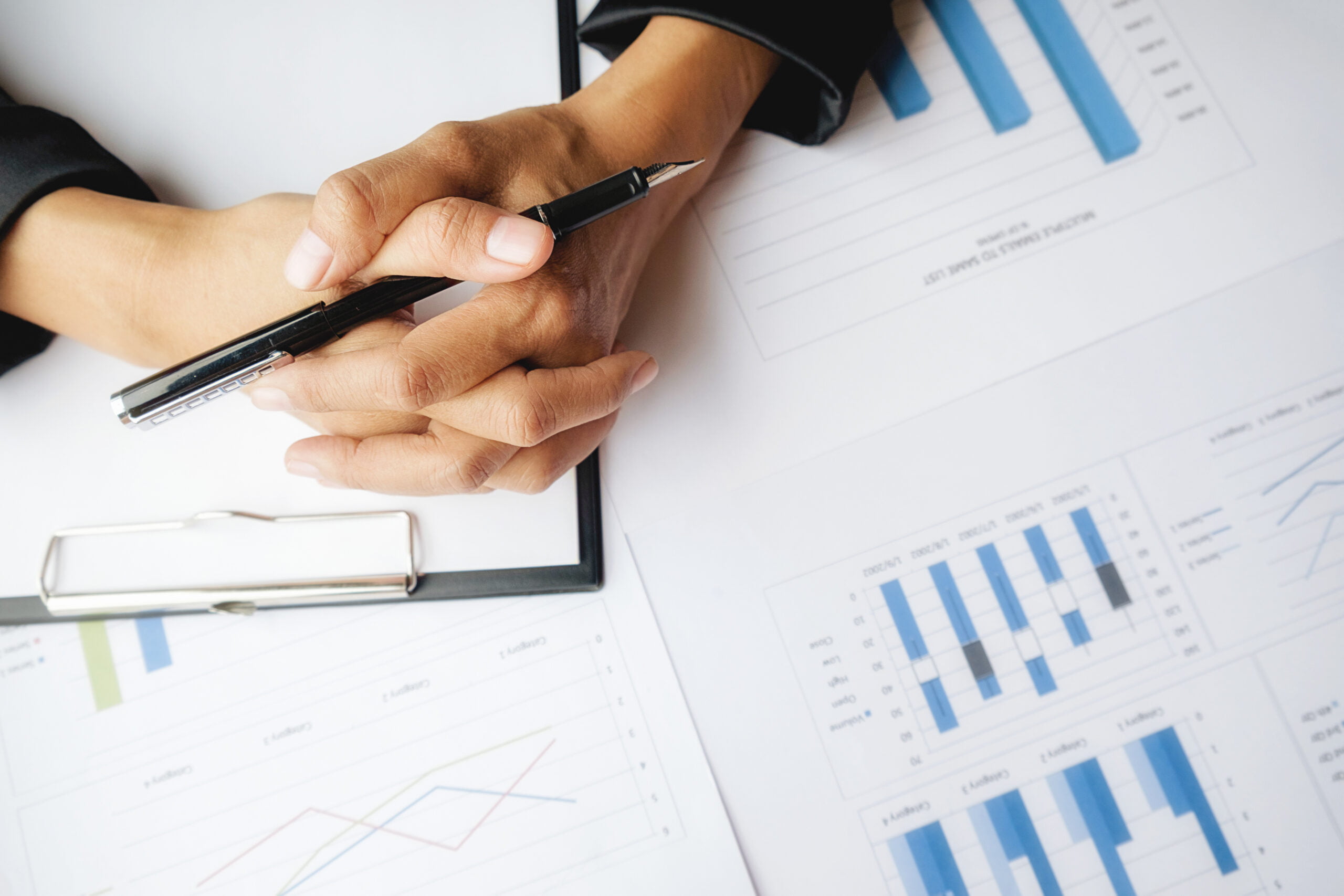 Dłonie księgowej spoczywają na dokumentach.