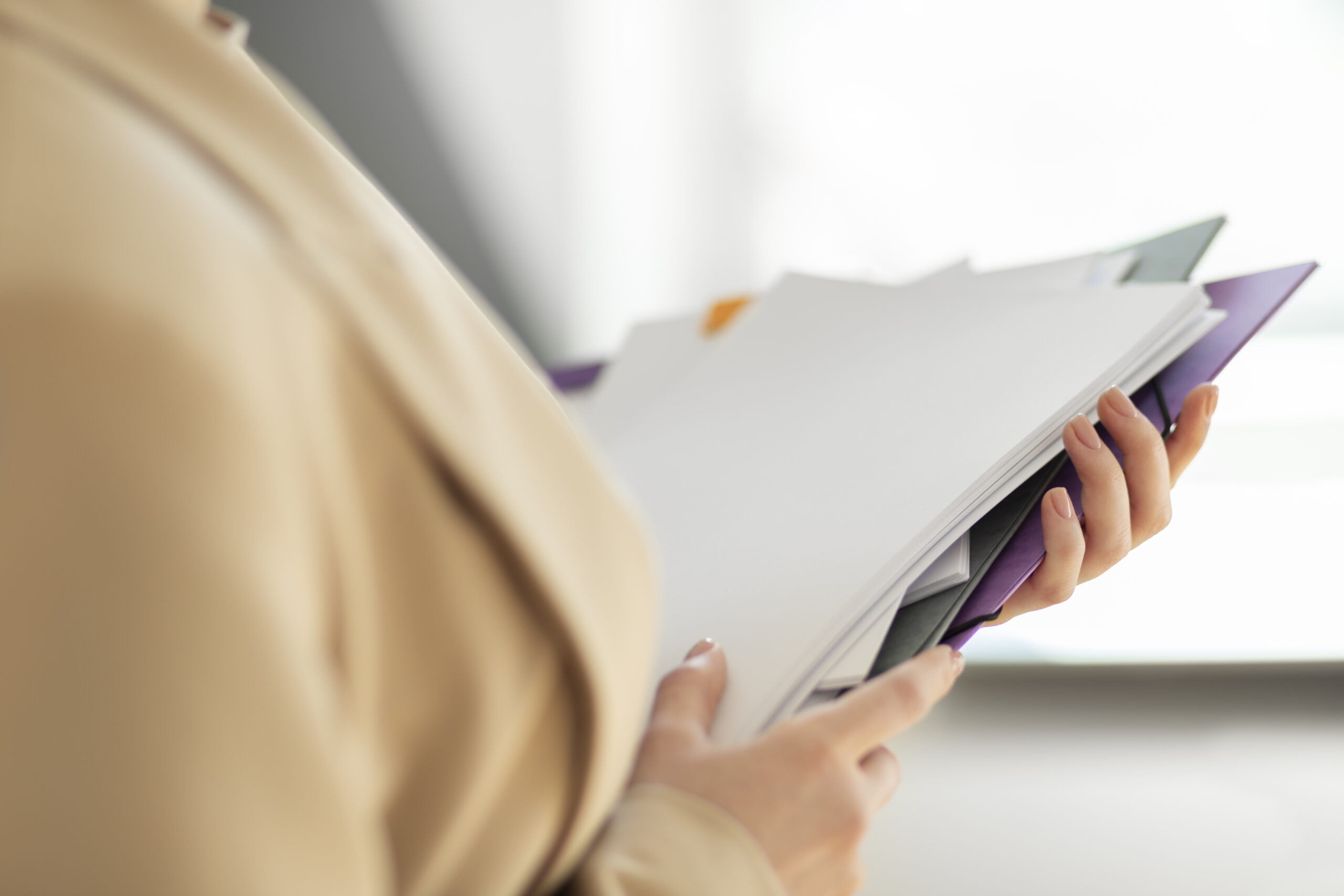 Zbliżenie na księgową trzymającą dokumenty księgowe.